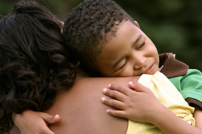 Un madre consuela a su pequeño niño enojado, la abraza con fuerza. El niño parece molesto y cansado.